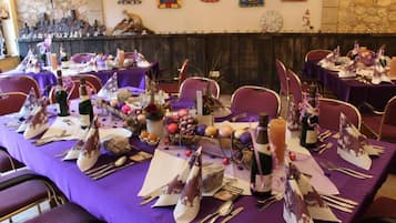 Un espace repas avec des nappes violettes, des tables soigneusement dressées avec des bouteilles de vin et des centres de table décoratifs.