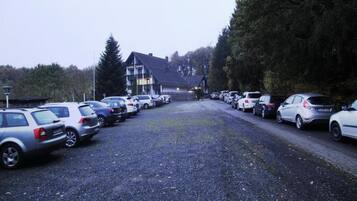Ett hotell med en grusparkering och flera parkerade bilar.