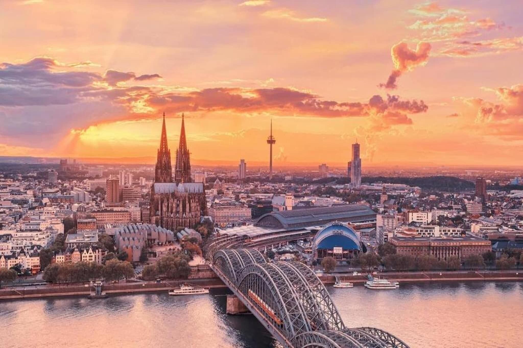 A cityscape with a prominent cathedral, a modern tower, and a bridge over a river.