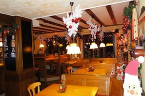 A restaurant interior with wooden tables and benches, festive decorations, and warm lighting. - Belvilla Heiderhof 3-bedroom apartment (Obersteinebach)