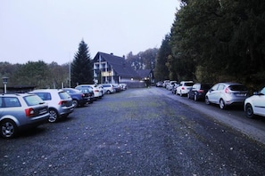 A hotel with a gravel parking lot and multiple parked cars. - Belvilla Heiderhof 3-bedroom apartment (Obersteinebach)