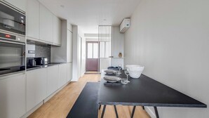 A modern kitchen with white cabinetry, a Bosch oven, and a black dining table set for two. - Spacious Apartment  a/c 1BR/4P - Notre-Dame (Paris)