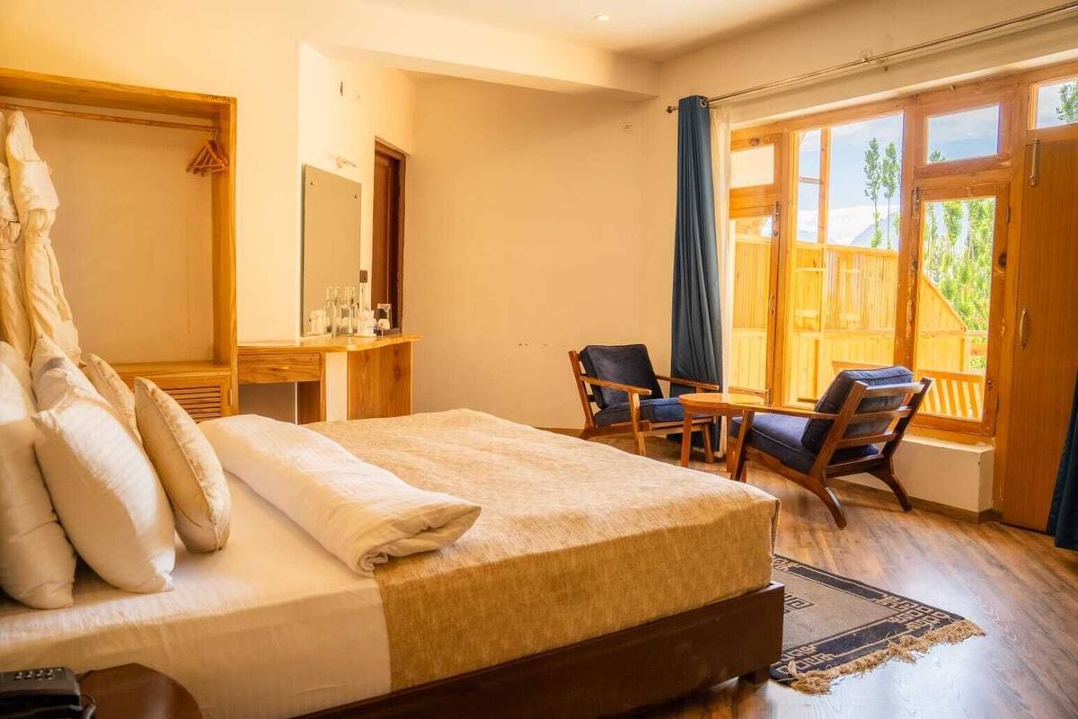 A bedroom with a bed, a desk, a chair, and a view through a window.