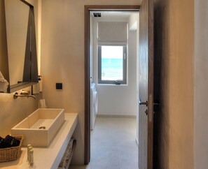 Un baño con un espejo grande, un lavabo y una ventana con vista al mar.