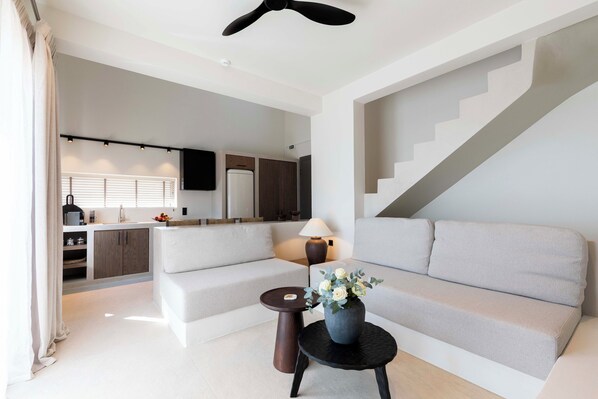 Una sala moderna con un sofá, una mesita con un jarrón y una escalera.