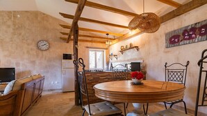 Una cocina con una mesa redonda de madera, sillas, un reloj y un ventanal.