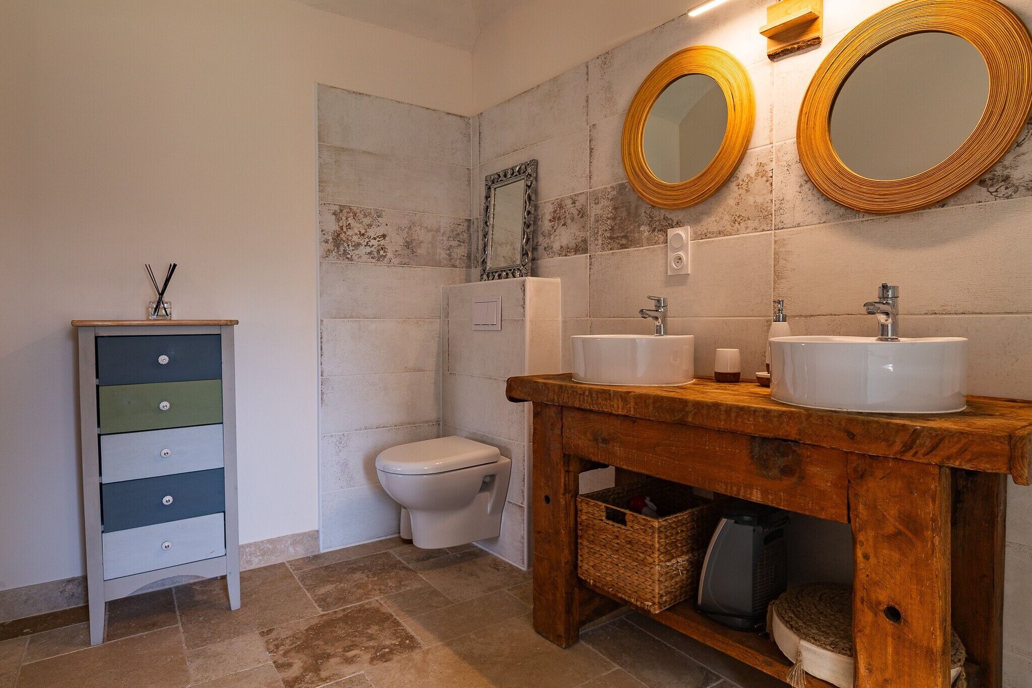 Un baño con tocador de madera, dos lavamanos, inodoro y espejo.