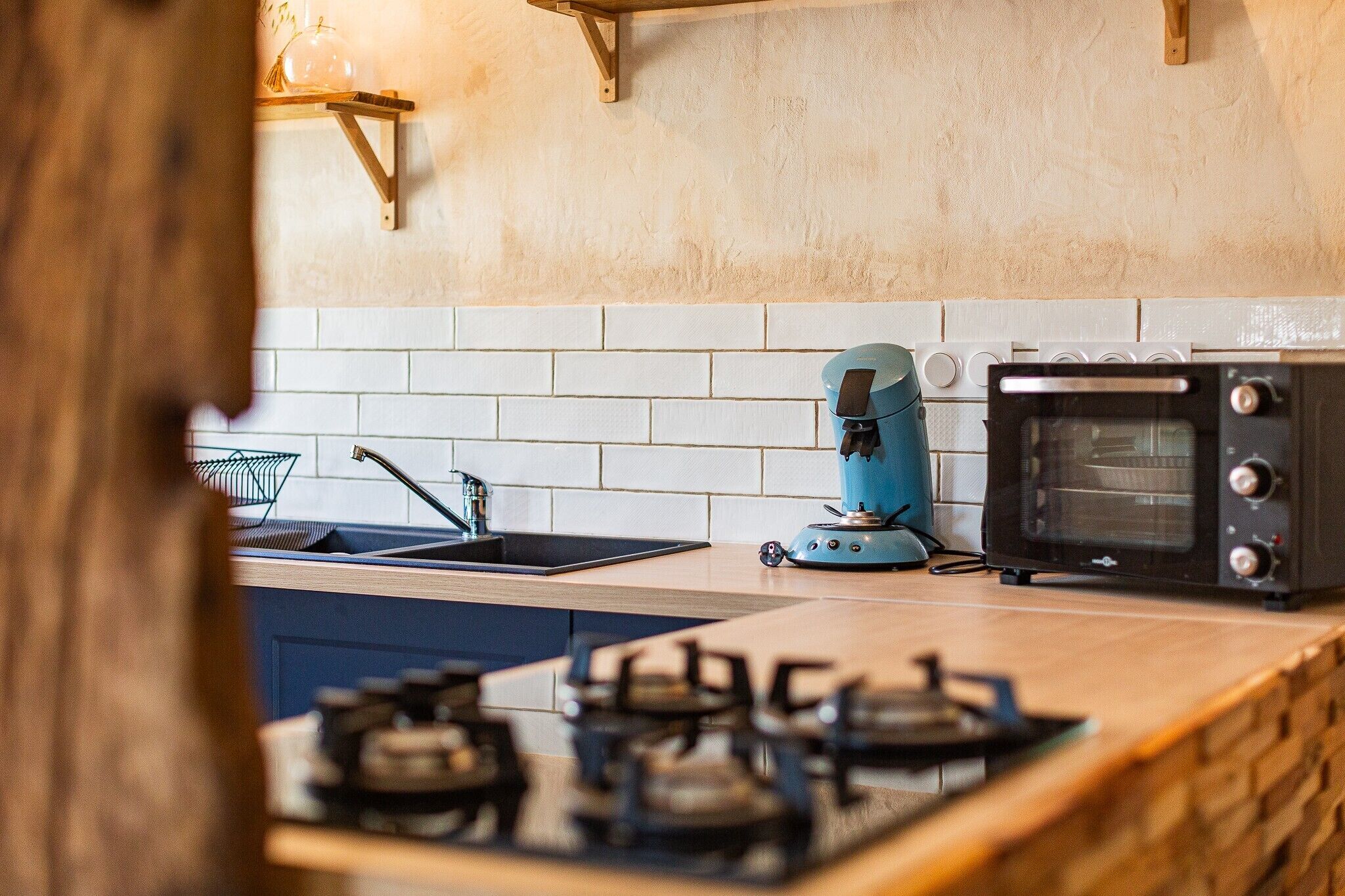 A kitchen with a gas stove, a coffee maker, and a toaster oven.