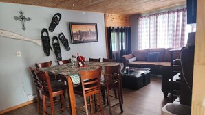 Un comedor con una mesa y sillas de madera, un sofá y un cuadro en la pared.