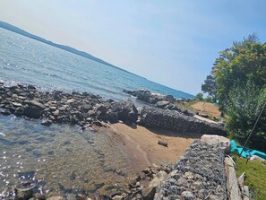 Una costa rocosa con agua cristalina, una playa de arena y un muro de piedra.