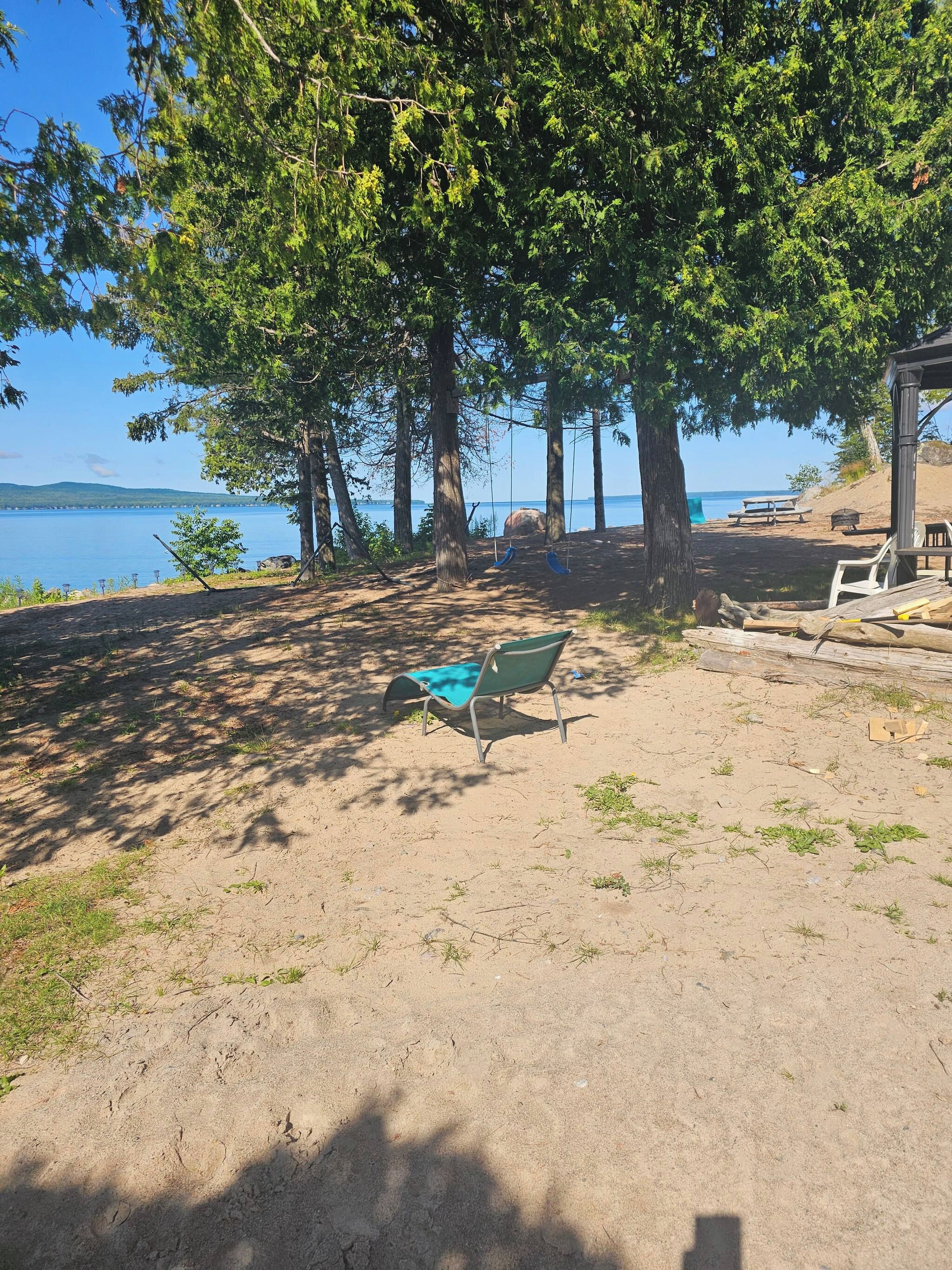 Une zone de plage sablonneuse avec une balançoire, un banc et un petit abri.