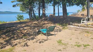 A sandy beach area with a swing set, a bench, and a small shelter.