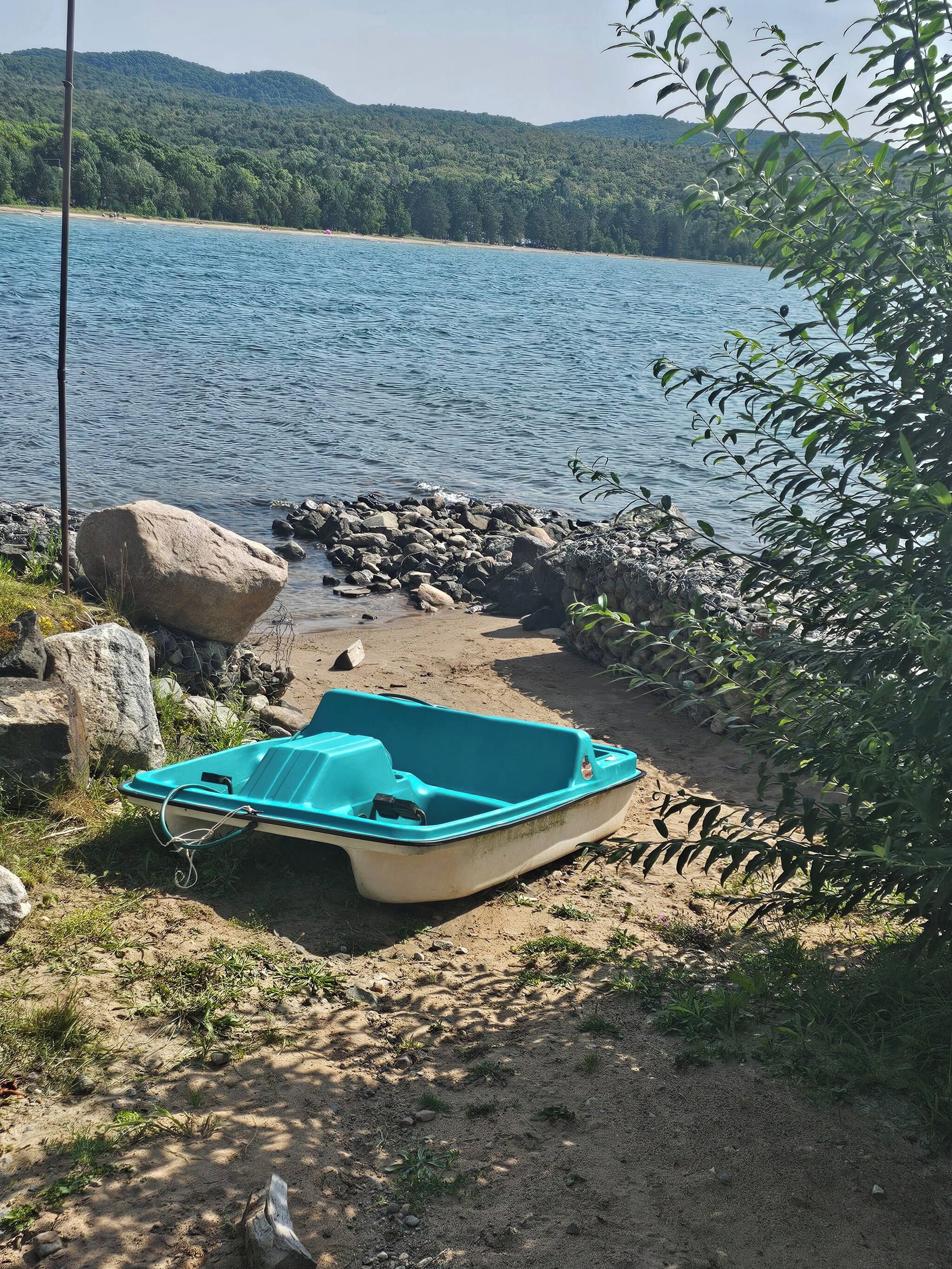 Un bateau sur une plage de sable, avec un lac et des collines en arrière-plan.
