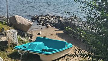 Un bateau sur une plage de sable, avec un lac et des collines en arrière-plan.