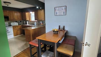 Une cuisine avec des meubles de rangement en bois, un four à micro-ondes et un panier de fruits posé sur le plan de travail.