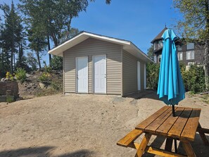 A small, single-story building with two white doors and a blue umbrella. - Lake Superior Waterffront Main Unit of Duplex Sleeps 8 ppl (Unorganized North Algoma)