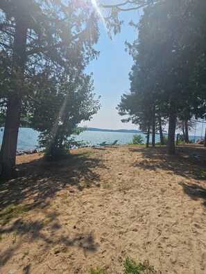 A beach with sand, trees, and a view of the water. - Lake Superior Waterffront Main Unit of Duplex Sleeps 8 ppl (Unorganized North Algoma)