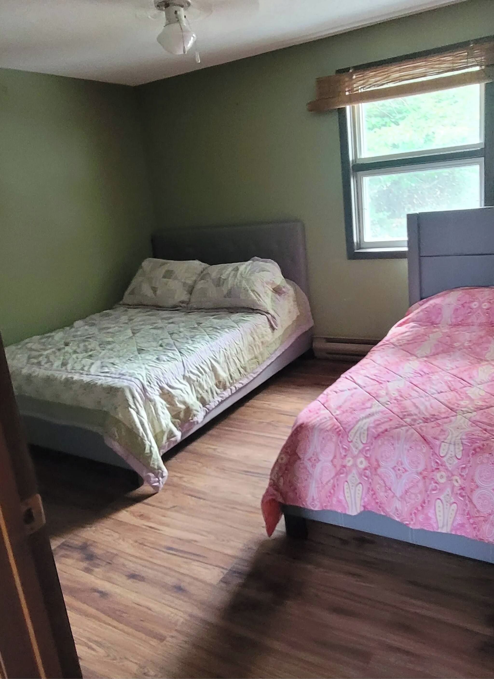 Une chambre avec deux lits, une fenêtre et un ventilateur de plafond.