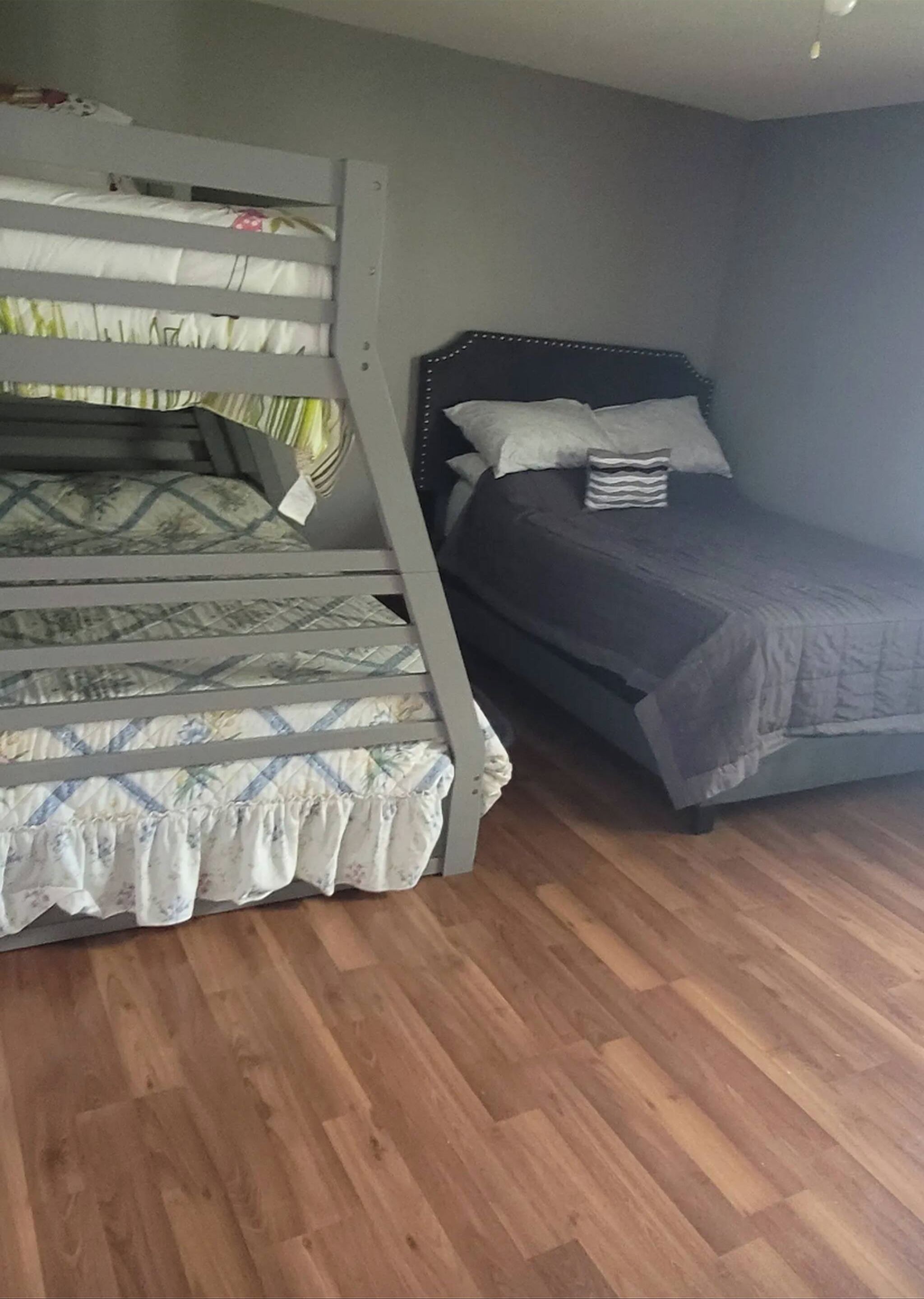 Une chambre avec deux lits superposés, l’un recouvert d’une couvre-lit à motifs et l’autre d’une couverture unie.