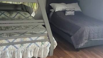 Une chambre avec deux lits superposés, l’un recouvert d’une couvre-lit à motifs et l’autre d’une couverture unie.