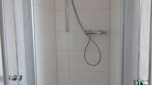 Ducha con cabezal de ducha de mano y grifo empotrado en la pared.