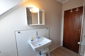A bathroom with a white sink, a mirror, and a wooden door. - Pithan Vacation Home - Pithan House in Werdum – Vacation home with a garden, Wi-Fi, and 4 (Werdum)