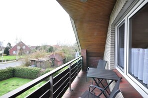 A balcony with a table and chairs, overlooking a residential area with houses and a road. - Pithan Vacation Home - Pithan House in Werdum – Vacation home with a garden, Wi-Fi, and 4 (Werdum)