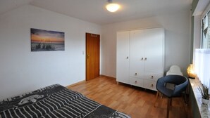 Una habitación con suelo de madera, un sofá, un armario y una silla.