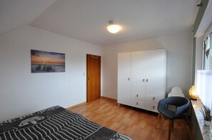 A room with a wooden floor, a sofa, a wardrobe, and a chair. - Pithan Vacation Home - Pithan House in Werdum – Vacation home with a garden, Wi-Fi, and 4 (Werdum)