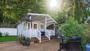 En træterrasse med en overdækket veranda, plantekasser og et bord med stole.