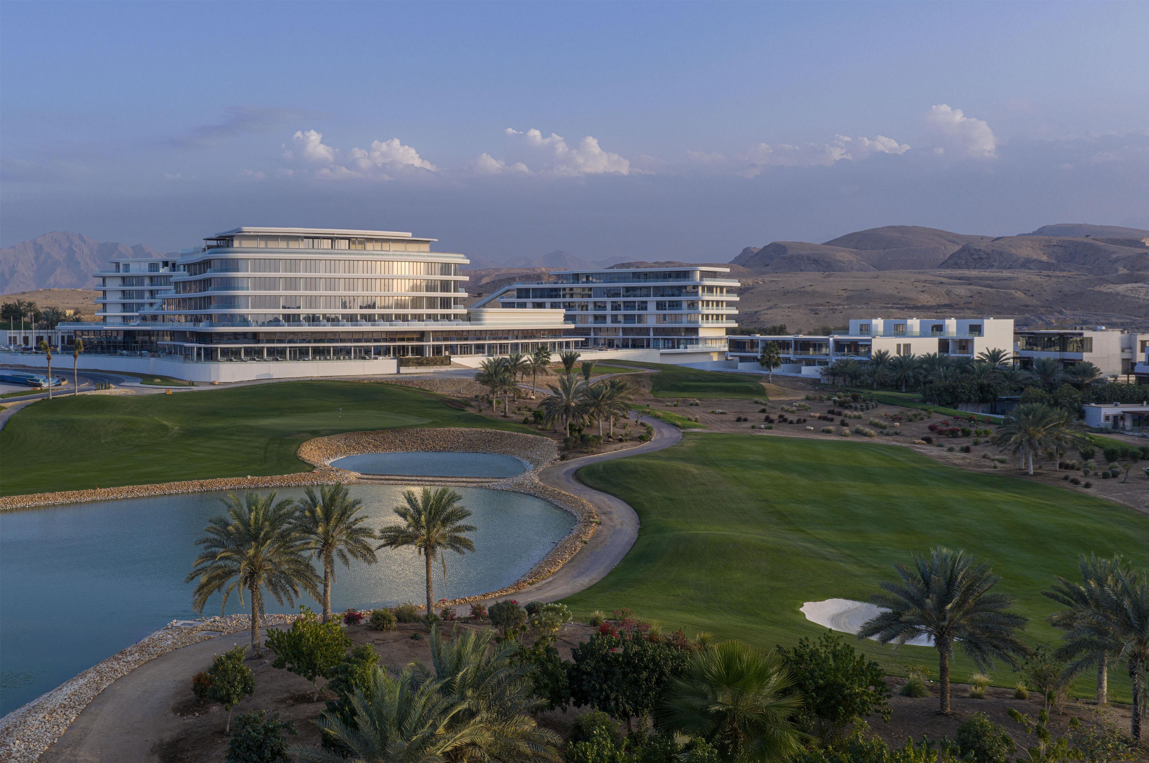 Un hotel moderno con piscina, campo de golf y paisaje desértico.