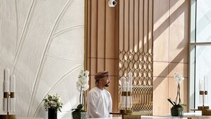 Uma área de recepção moderna com balcões de mármore, uma parede decorativa e uma câmera de segurança.