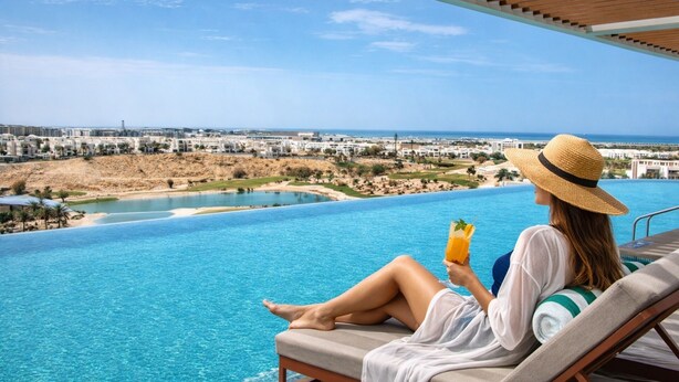 Uma pessoa relaxando à beira da piscina, com vista para a paisagem urbana costeira.