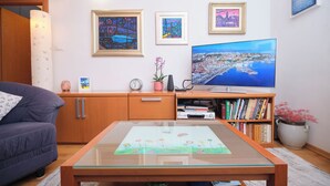 A living room with a sofa, a coffee table with a drawing, a TV, a bookshelf, and framed pictures on the wall. - Old Town Art Apartment Split by Litto (Split)
