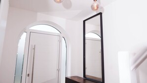 Een moderne badkamer met een grote spiegel, een houten wastafelmeubel en een plafondlamp.