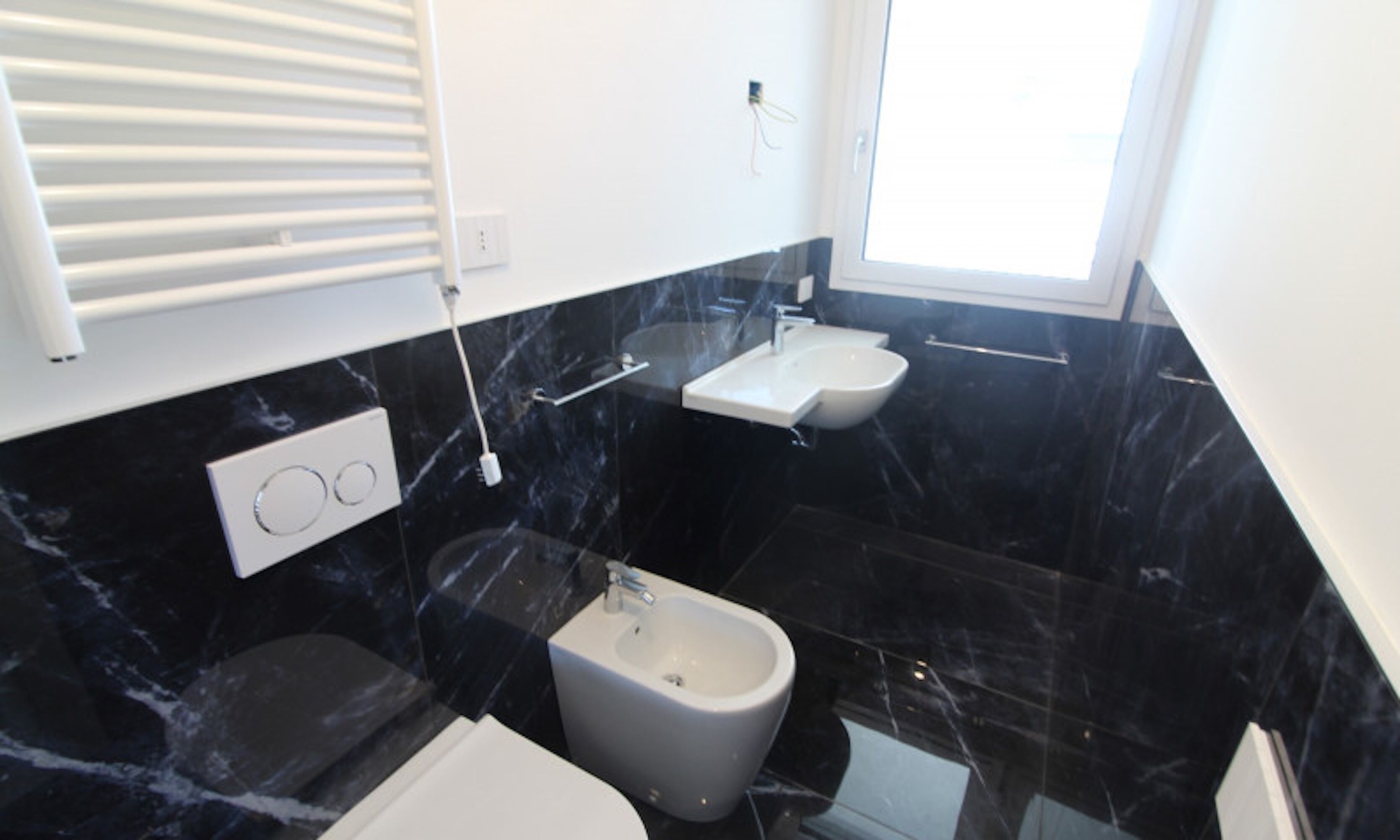 Un baño moderno con un bidé, un lavamanos y un inodoro.