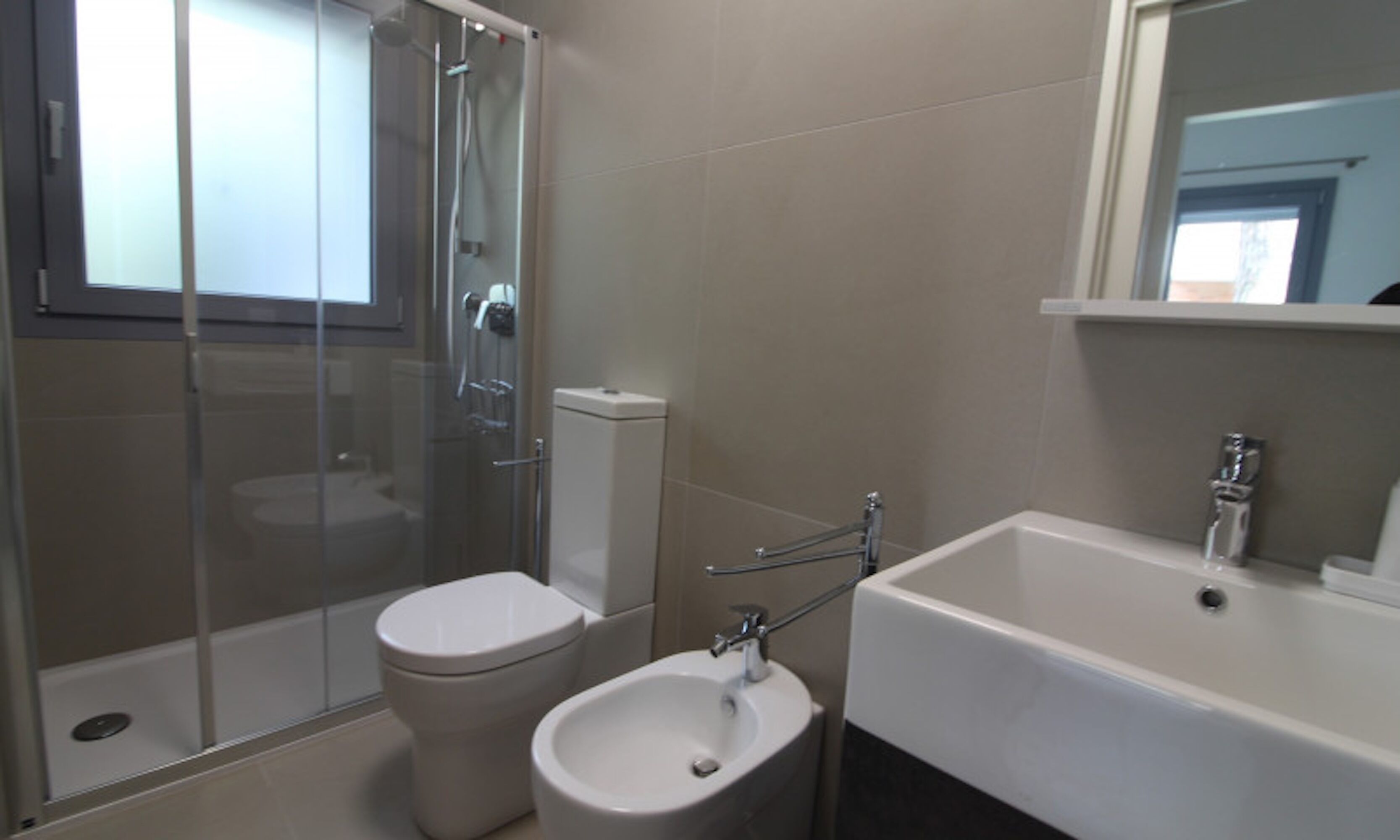 A modern bathroom with a glass-enclosed shower, a toilet, and a sink with a mirror above it.