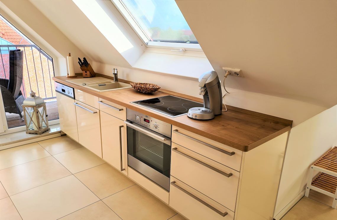 Een moderne keuken met dakraam, inbouwoven en houten aanrecht.