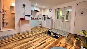 Una cocina moderna con armarios azul claro, un refrigerador blanco y un microondas. Hay piso de madera y una alfombra pequeña frente a la puerta.