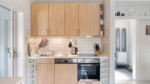 Eine moderne Küche mit Holzschränken, einem Geschirrspüler, einem Backofen und einer Spüle.