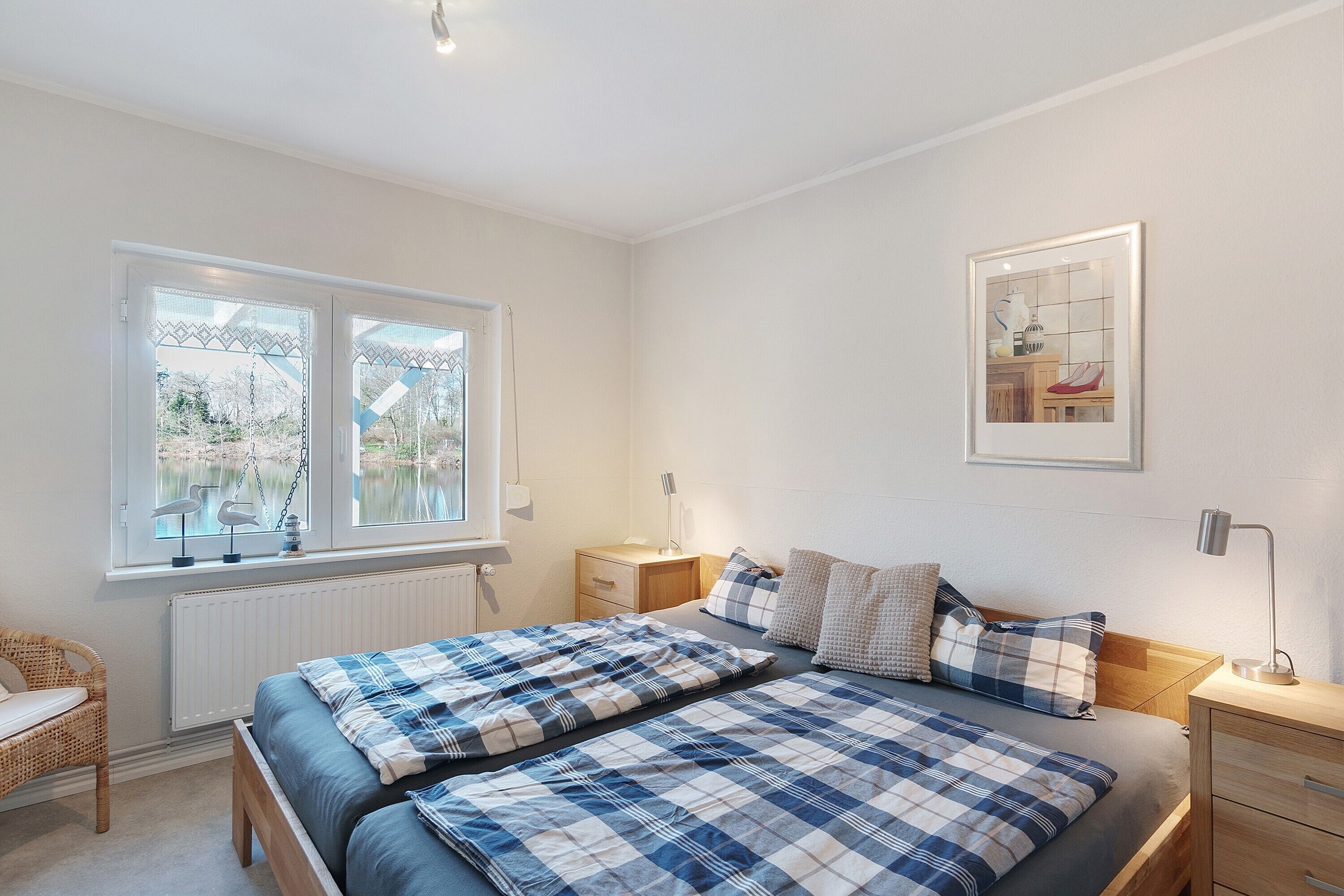 Ein Schlafzimmer mit einem Bett, Nachttischen, einem Fenster und einem gerahmten Bild an der Wand.