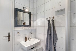 Ein Badezimmer mit einem weißen Waschbecken, einem Spiegel und einem Handtuchhalter.