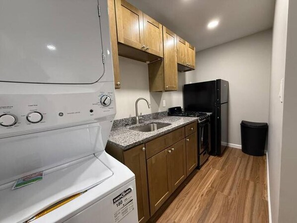 A compact kitchen with wooden cabinets, a built-in sink, a stove, and a refrigerator.