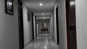 Un corridoio con porte su entrambi i lati, pavimento piastrellato e una luce a soffitto.