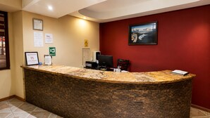 Una reception con una scrivania, un computer, una sedia e un quadro appeso al muro.