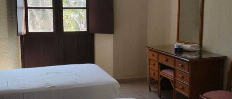 A hotel room with two beds, a desk, a chair, a mirror, and a TV.