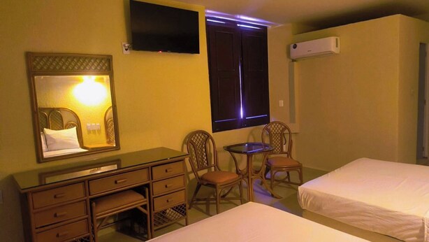 Habitación de hotel con cama, escritorio, dos sillas, televisión y aire acondicionado.