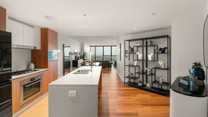 Una cocina moderna con una isla central, armarios de madera y encimera negra.