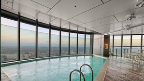 Un edificio alto con una amplia piscina cubierta, grandes ventanales y vistas a la ciudad.