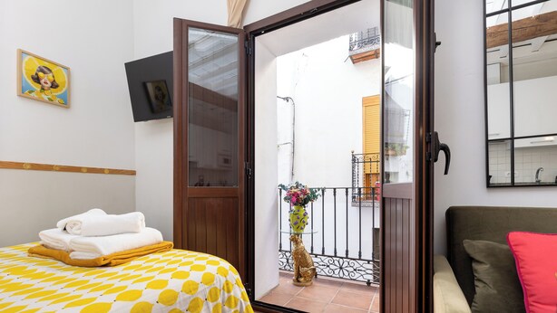 Une chambre d’hôtel comprenant un lit, un canapé, un balcon avec une balustrade et une fenêtre.